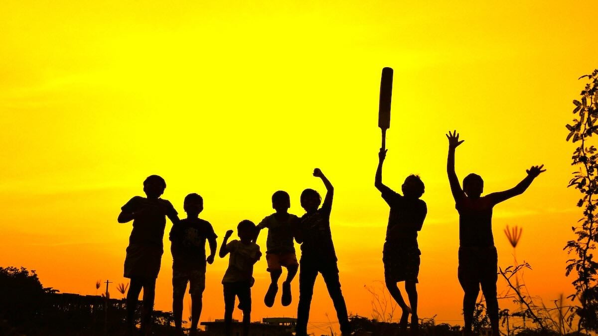 Children playing cricket during sunset