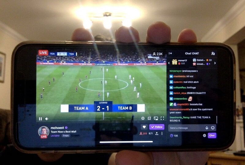 Smartphone screen showing Twitch stream with professional scoreboard overlay displaying live match score and time